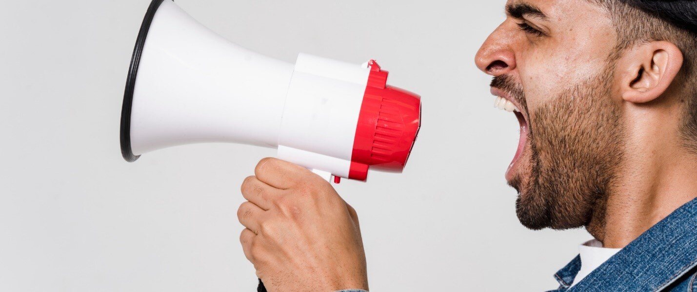 A person holding a megaphone

Description automatically generated